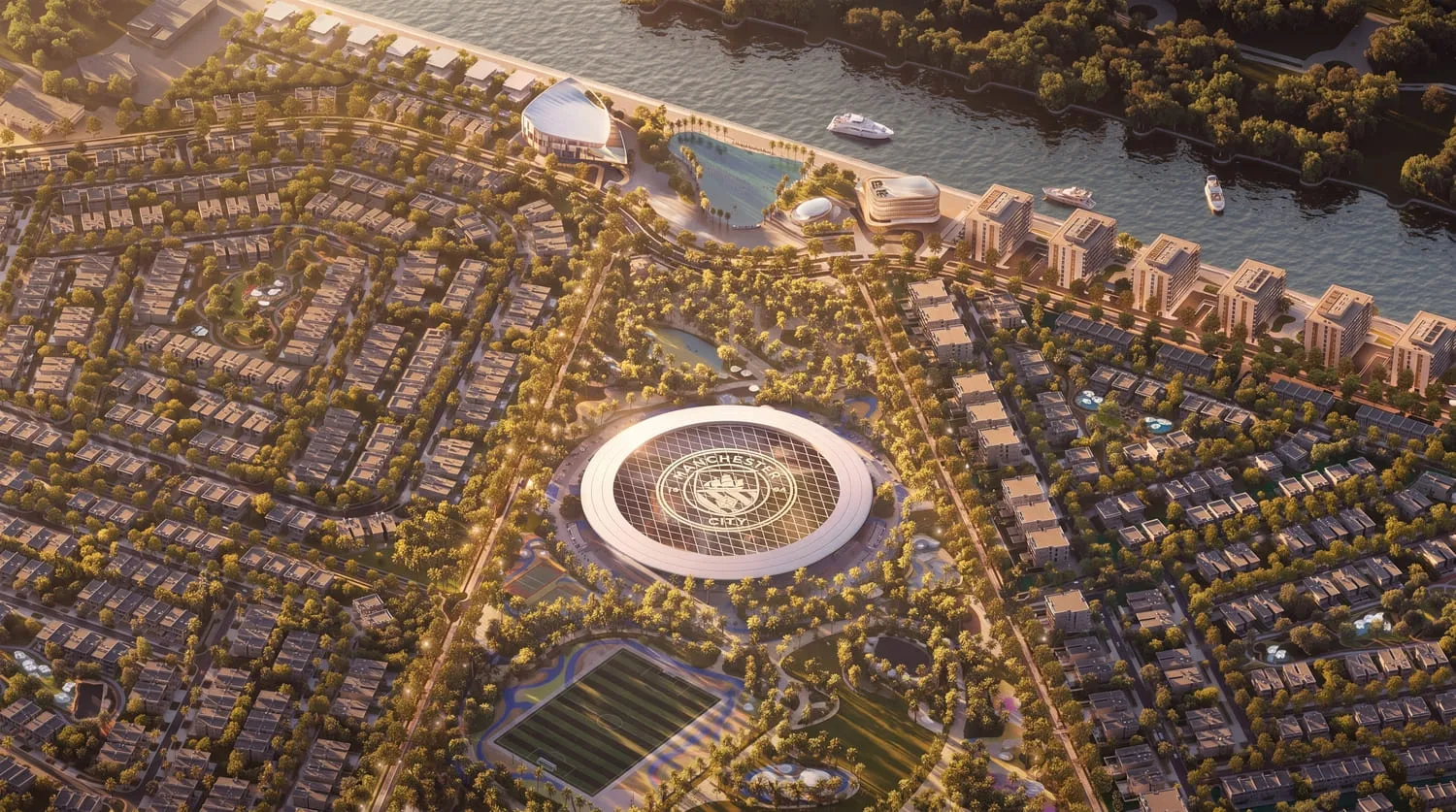 Aerial view of the masterplan at dusk: the circular Manchester City Park landmark at the centre of a grid of villas and townhouses, with the canal and low-rise blocks along the water at the top